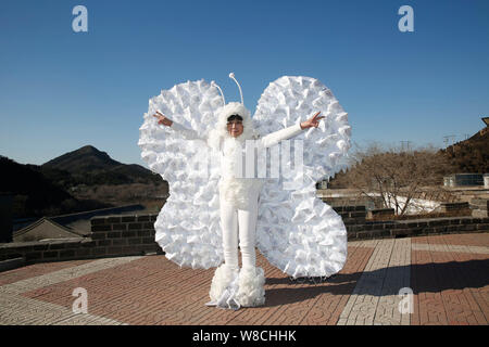 L'artiste chinois Kong Ning, droit, vêtu d'un costume de papillon fait avec 365 masque de visage pose à la Grande Muraille de Badaling, à la périphérie de Beijing, Banque D'Images