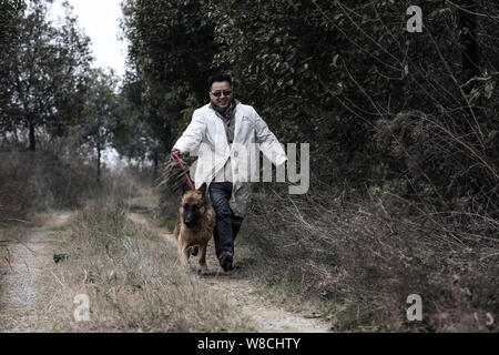 Du ventilateur marche un chien à l'adoption d'un animal errant à Wuhan de base, le centre de la Chine la province du Hubei, du 26 décembre 2014. Du ventilateur, un 32-year-old man, vête Banque D'Images