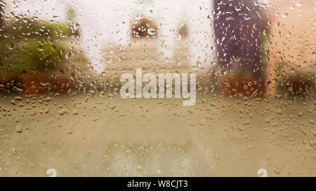 Gouttes de pluie sur la surface du panneau de verre fenêtre humide en saison des pluies. Résumé fond. Modèle naturel des gouttes isolées de l'extérieur de la ville floues dans Banque D'Images