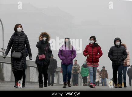 --FILE--piétons, la plupart d'entre eux porter des masques, à pied dans une rue de smog lourde à Beijing, Chine, 25 décembre 2015. Les habitants de Beijing ont acheté plus de Banque D'Images