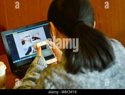 --FILE--Une femme chinoise utilise son smartphone Apple iPhone 4S et un ordinateur portable pour parcourir les photos en ligne dans la ville de Hangzhou, Zhejiang en Chine est de bauvin Banque D'Images