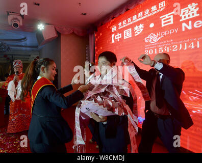 Gagnant du premier prix Li Gang porte un foulard et est titulaire d'un bouquet de fleurs, les deux 100-yuan billets en euros, au cours de la fête annuelle d'une entreprise en Chen Banque D'Images