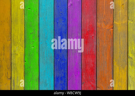 Close-up d'un mur ou une clôture en bois arc-en-ciel peint un temps très long et la peinture écaillé. Fond amusant pour les enfants et un décor design. Banque D'Images