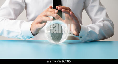 Vue avant du geste de protection dans les mains des hommes sur une boule de cristal rayonnant de poussière magique dans une image conceptuelle. Banque D'Images