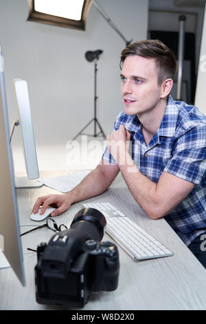 Homme Photographe en studio l'examen des images de la séance photo sur l'ordinateur Banque D'Images