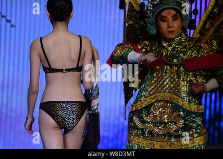 Un modèle en maillot affiche un sac de luxe comme un acteur d'opéra de Pékin effectue lors d'un fashion show à Jinan city, est de la Chine.s la province de Shandong, 11 N Banque D'Images