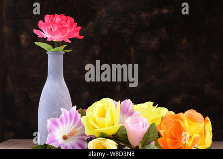 Fleurs artificielles multicolores de types différents sur une table en bois. Banque D'Images