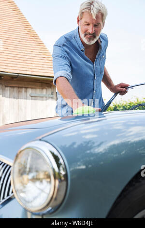 Homme mature restauré Polissage Voiture de sport classique dehors à la maison Banque D'Images