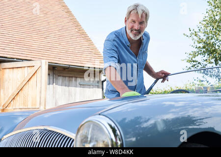 Portrait d'homme mûr restauré Polissage Voiture de sport classique dehors à la maison Banque D'Images