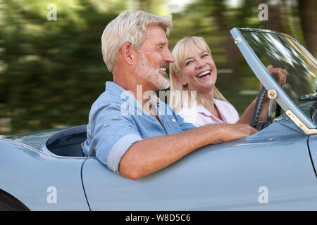 Mature Couple Enjoying Road Trip In Classic Open Top Voiture de sport Ensemble Banque D'Images