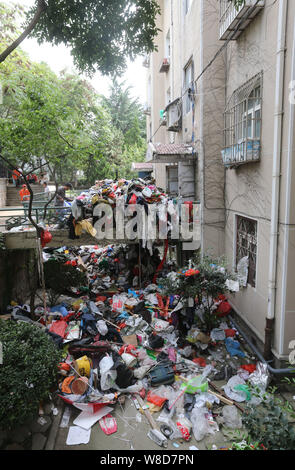 Les travailleurs chinois à l'assainissement de dissiper un tas de détritus accumulés par une personne âgée en face d'un immeuble d'appartements dans la ville de Qingdao, Chine de l'Est. Banque D'Images