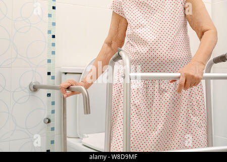 Femme âgée tenant sur la main courante dans les toilettes. Banque D'Images