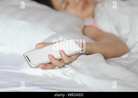 Woman sleeping in bed and holding a cell phone. Banque D'Images