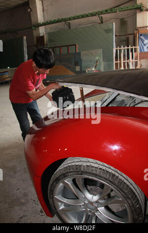 Les jeunes Chinois Chen Yinxi vérifie sa voiture de sport électrique fait maison à l'atelier de sa famille dans l'usine Haikou City, Chine du sud de Hainan provin Banque D'Images