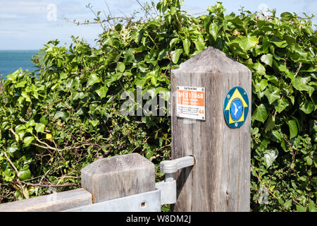 Marqueur de référence grille affiche bilingue sur Anglesey Coastal Path gate post avec informations d'urgence. Helaeth Porth Llangefni Isle of Anglesey Pays de Galles UK Banque D'Images