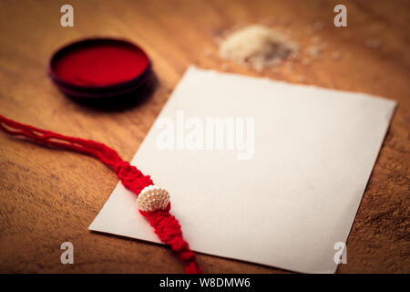Libre shot of handmade Rakhi ou threads sur une surface en bois avec kumkum, chawal et livre blanc pour copier l'espace. Concept pour Raksha Bandhan greeting Banque D'Images