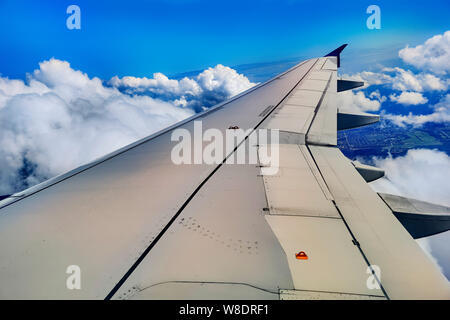 Aile d'avion au-dessus des nuages. Une aile d'avion au-dessus des nuages à midi vu à travers une fenêtre d'un aéronef, couleur tonique travel concept photo Banque D'Images