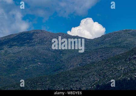 Puffy blanc pop nuage de derrière les montagnes près de la ville de Ioannina, Grèce Banque D'Images