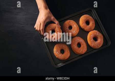 Homme tenez le donut avec couche de sucre sur le plateau Banque D'Images