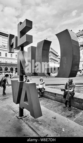 Gênes, Italie - 6 juillet 2019 : Genova plus de ce signe (logo) de la ville et les personnes se trouvant à proximité de la place de Ferrari à Gênes. Image en noir et blanc Banque D'Images