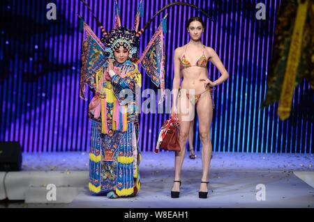 Un modèle en maillot affiche un sac de luxe comme un acteur d'opéra de Pékin effectue lors d'un fashion show à Jinan city, est de la Chine.s la province de Shandong, 11 N Banque D'Images