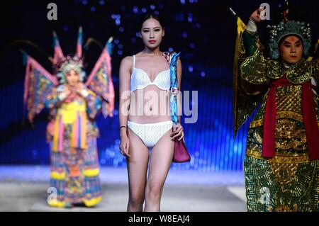 Un modèle en maillot affiche un sac de luxe comme acteurs de l'Opéra de Pékin effectuer sur la même scène lors d'un défilé dans la ville de Jinan, est de la Chine.s Shandon Banque D'Images
