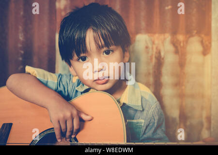 Asian boy playing acoustic guitar avec de vieux fond acier Banque D'Images