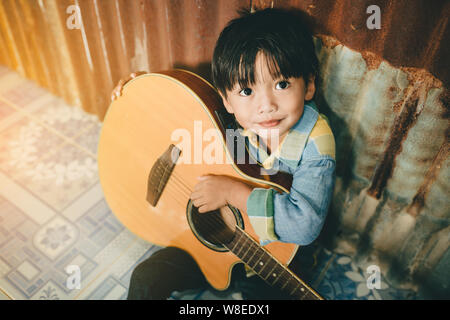 Asian boy playing acoustic guitar avec de vieux fond acier Banque D'Images