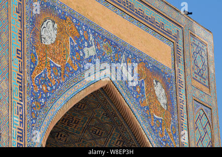 Mosaïques de tigre et de soleil à face humaine dans le pishtaq de Sher-Dor Madrasah, Registan, Samarcande, Ouzbékistan Banque D'Images