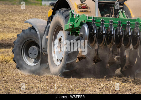 Tracteur jaune avec le cultivateur tournant sur le terrain vue arrière Banque D'Images