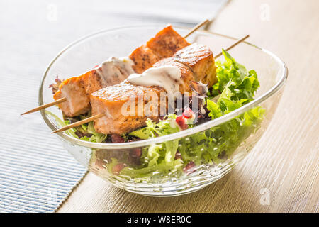 Les brochettes de saumon grillé avec de la laitue d'été salat pomehranate graines huile d'olive et vinaigrette. L'alimentation des poissons en bonne santé avec des fruits et légumes Banque D'Images