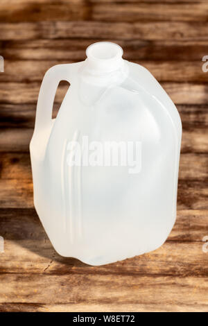 Les emballages vides en plastique blanc gallon isolé sur fond de table en bois. Banque D'Images