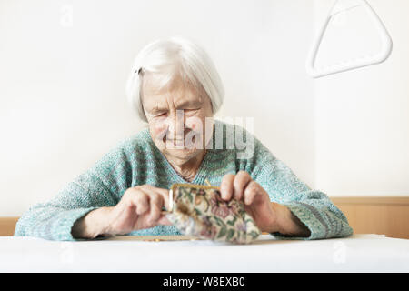 Personnes âgées gaies 96 ans woman sitting at table à la maison heureux avec elle dans son portefeuille d'épargne-retraite après le paiement des factures. Banque D'Images