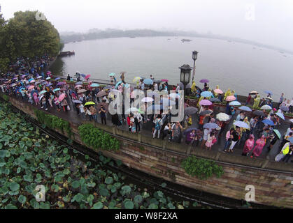 Les touristes des parasols à pied par le pont cassé sur le lac de l'Ouest dans la pluie dans la ville de Hangzhou, Zhejiang Province de Chine orientale, 4 octobre 2 Banque D'Images
