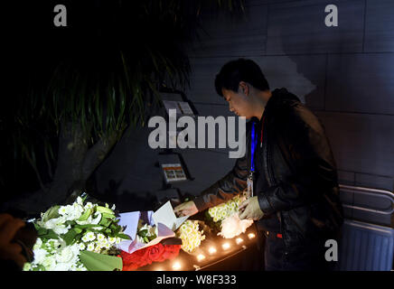 Un Chinois jette des fleurs pour les victimes du 13 novembre Paris les attaques à l'Ambassade de France à Pékin, Chine, 14 novembre 2015. Banque D'Images