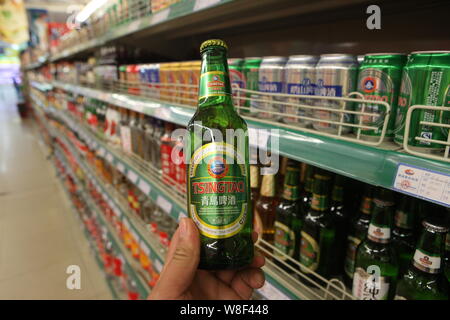 --FILE--qu'un client achète une bouteille de Bière de Tsingtao Tsingtao Brewery dans un supermarché à Shanghai, la Chine de l'est la province de Shandong, le 5 juillet 2014. Banque D'Images