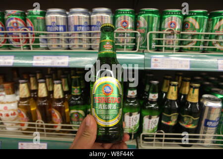 --FILE--qu'un client achète une bouteille de Bière de Tsingtao Tsingtao Brewery dans un supermarché à Shanghai, la Chine de l'est la province de Shandong, le 7 mai 2014. Je Banque D'Images