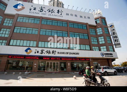 --FILE--Chinese cyclistes roulent un vélo électrique passé une succursale de la Banque de Shanghai à Chongqing city, province de Jiangsu en Chine de l'Est, 6 avril 2014. O Banque Banque D'Images