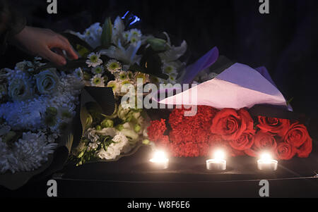 Un Chinois jette des fleurs pour les victimes du 13 novembre Paris les attaques à l'Ambassade de France à Pékin, Chine, 14 novembre 2015. Banque D'Images