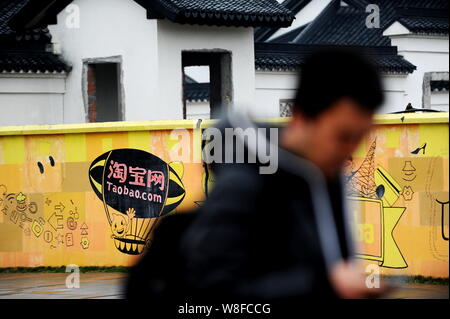 --FILE--un piéton marche dernières graffiti de marché en ligne Taobao.com au siège de Groupe d''Alibaba à Hangzhou City, Zhejiang en Chine de l'Est Banque D'Images