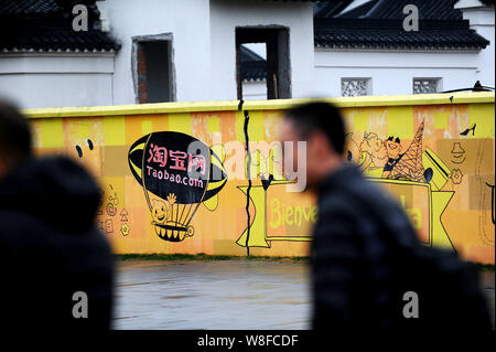 --FILE--piétons à pied passé graffiti de magasinage en ligne Taobao.com site sur un mur au siège de Groupe d''Alibaba à Hangzhou city, est de la Chine" Banque D'Images