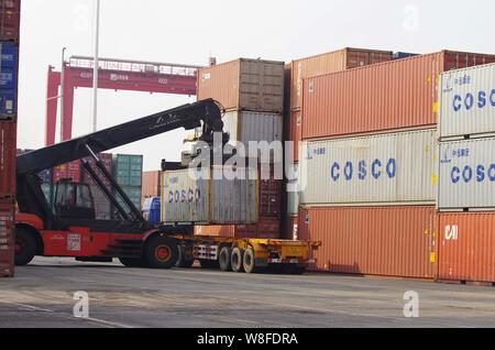 --FILE--une grue véhicule charge un camion avec un récipient de COSCO dans le port de Shanghai à Shanghai, la Chine de l'est la province de Shandong, 8 mars 2015. Banque D'Images