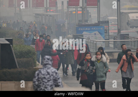 Piétons, beaucoup d'entre eux porter des masques, à pied dans une rue de smog lourds à Shenyang city, Liaoning Province du nord-est de la Chine, le 8 novembre 2015. Un Banque D'Images