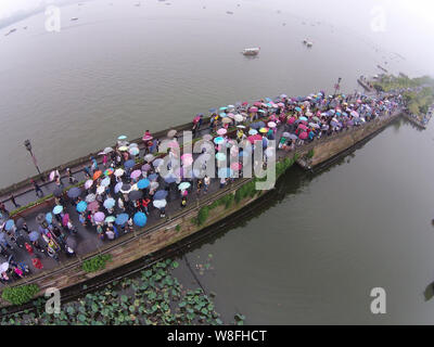 Les touristes des parasols à pied par le pont cassé sur le lac de l'Ouest dans la pluie dans la ville de Hangzhou, Zhejiang Province de Chine orientale, 4 octobre 2 Banque D'Images
