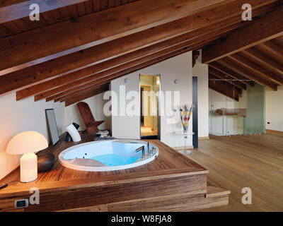 Photos de l'intérieur d'une salle de bains moderne dans la chambre mansardée à l'avant-plan la baignoire à remous le sol et le plafond sont faits de bois Banque D'Images