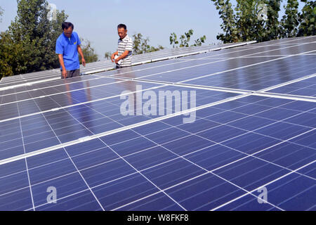 --FILE--travailleurs chinois vérifier des panneaux solaires à une centrale photovoltaïque dans Zhengzhuang Jiazhai village, ville, comté de Chiping, Linyi city, à l'Est Banque D'Images