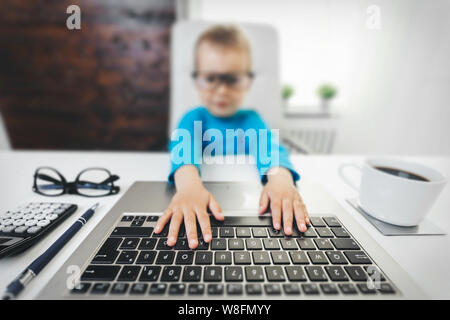 Enfant mignon avec des lunettes l'apprentissage de l'utilisation d'un ordinateur portable Banque D'Images