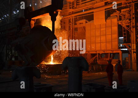 --FILE--regarder les travailleurs chinois de l'acier en fusion est versé dans un four d'affinage à l'usine sidérurgique à Qiqihar, ville du nord-est de la Chine Shandong en pro Banque D'Images