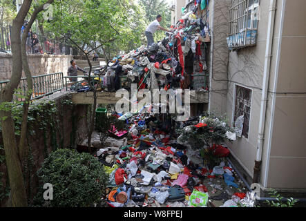 Les travailleurs chinois à l'assainissement de dissiper un tas de détritus accumulés par une personne âgée en face d'un immeuble d'appartements dans la ville de Qingdao, Chine de l'Est. Banque D'Images