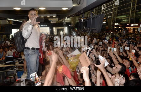 La star du football italien Fabio Cannavaro, haut, ancien entraîneur en chef de la Chine Guangzhou Evergrande FC Taobao, prend des photos de fans chinois avant de quitter C Banque D'Images